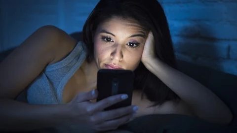 Una mujer mira el móvil en la oscuridad