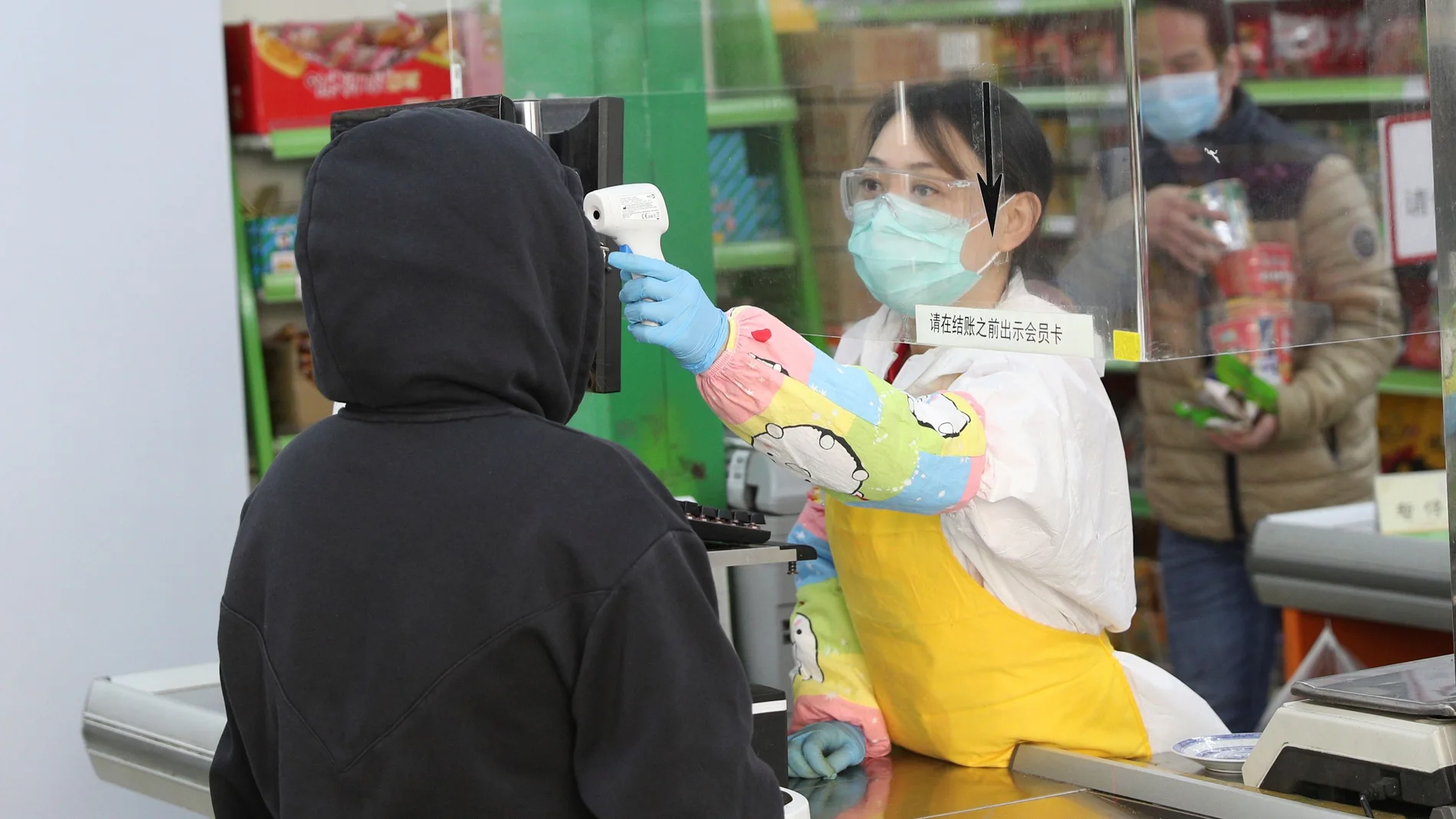 Una trabajadora usa un termómetro de infrarrojos para tomar la temperatura a los clientes durante la reapertura del supermercado Asia, en el barrio madrileño de Usera este miércoles. EFE/Rodrigo Jiménez