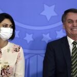 Brazil's President Jair Bolsonaro smiles sitting next to his wife Michelle Bolsonaro wearing a protective face mask, during the swearing ceremony of his new justice minister, at the Planalto presidential palace, in Brasilia, Brazil, Wednesday, April 29, 2020. (AP Photo/Eraldo Peres)