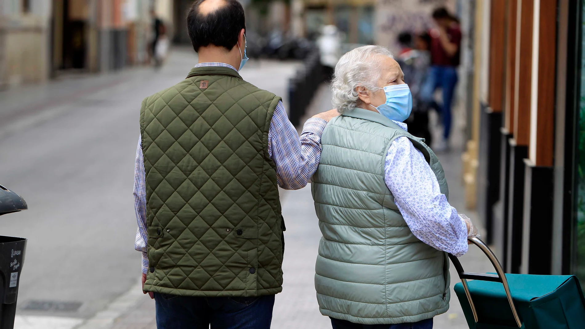 Dos ciudadanos con mascarilla por Sevilla