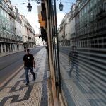 Un hombre protegido con una visera de plástico camina por la calle del centro de Lisboa