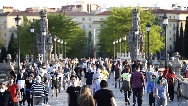 Numerosas personas atraviesan el Puente de Toledo de Madrid