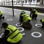 Trabajadores colocan señales de plástico en el suelo de la estación de la Gare du Nord para mantener la distancia social