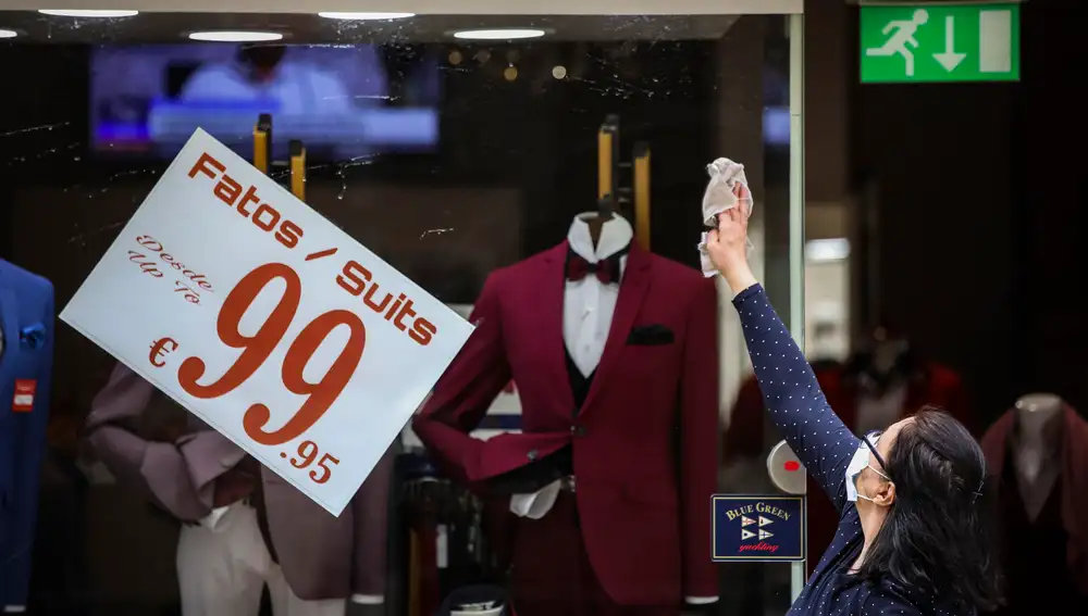 Una mujer prepara su tienda de moda en Lisboa para la reapertura comercial que arrancó el 4 de mayo
