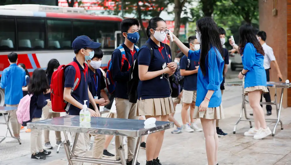 Estudiantes con mascarillas y sometiéndose a las nuevas medidas de higiene antes de entrar en la escuela Marie Curie en Hanoi