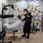 Un empleado de la peluquería Emilio, abierta durante el día 51 del estado de alarma, corta el pelo a un cliente