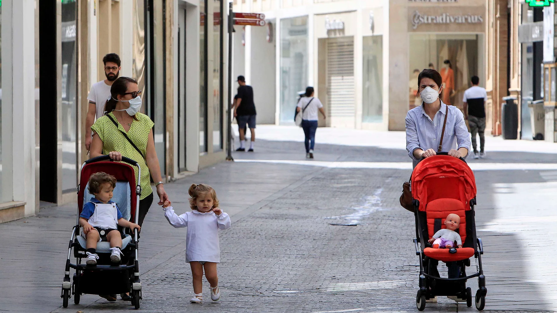 Una familia con niños pasea por la sombra en una calle peatonal de Sevilla