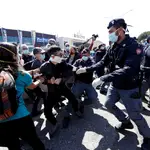 Un policía con mascarilla trata de contener una protesta de los familiares de los presos pidiendo mejores condiciones en la prisión de Rebibbia