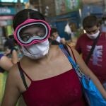 A woman wears a scuba and surgical mask amid the spread of the new coronavirus while shopping at a market in Lima, Peru, Monday, March 23, 2020. (AP Photo/Rodrigo Abd)