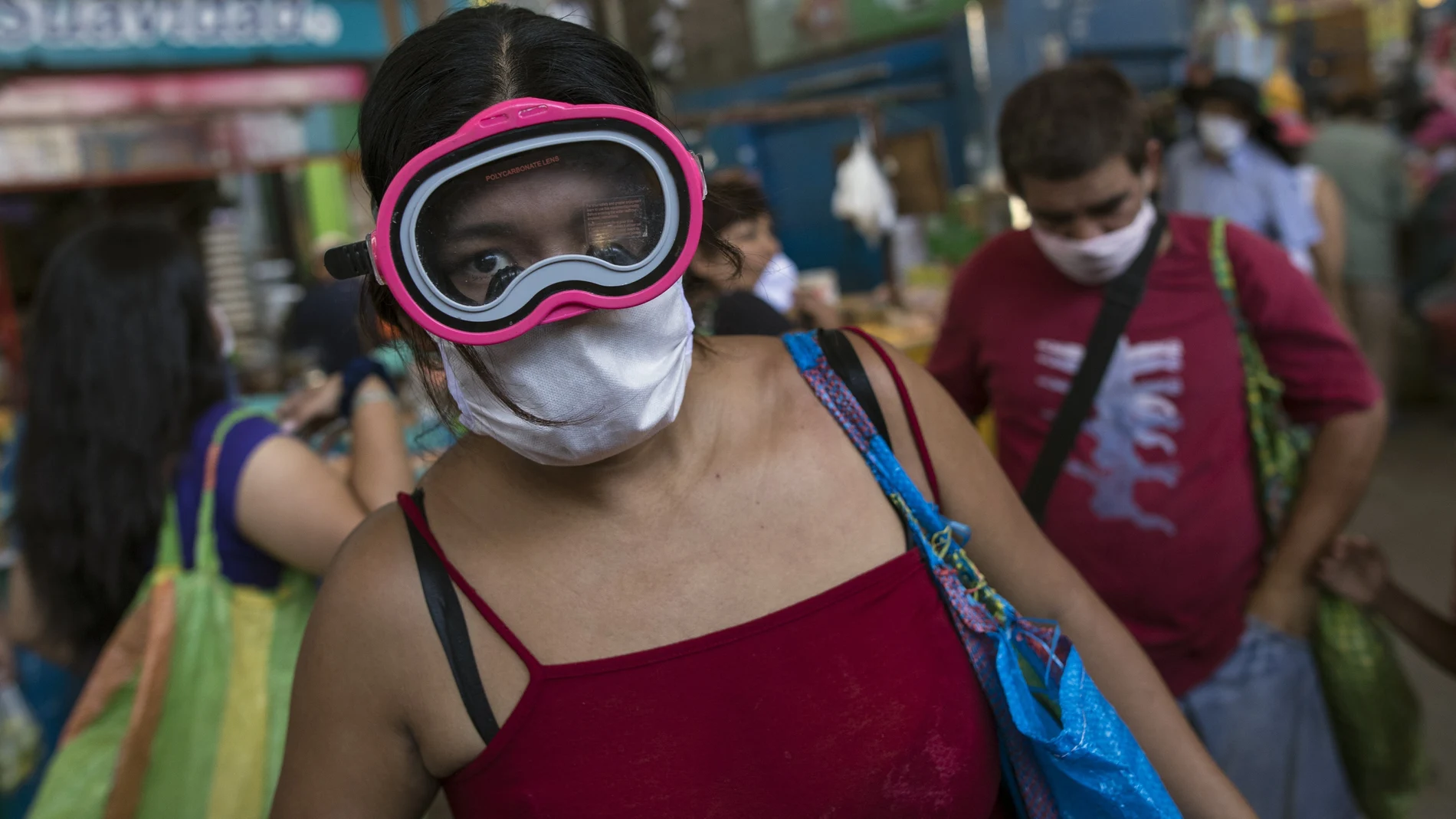 A woman wears a scuba and surgical mask amid the spread of the new coronavirus while shopping at a market in Lima, Peru, Monday, March 23, 2020. (AP Photo/Rodrigo Abd)