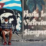 HAB01. LA HABANA (CUBA), 07/05/2020.- Un hombre con tapabocas revisa en su celular, junto a un graffitis con la imagen del guerrillero argentino-cubano Ernesto Che Guevara, este jueves en La Habana (Cuba). efe/Ernesto Mastrascusa