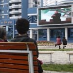 Norcoreanos en un parque de Pyongyang observan una pantalla gigante que muestra al líder norcoreano en la inauguración de una planta de fertilizantes este sabádo 2 de mayo