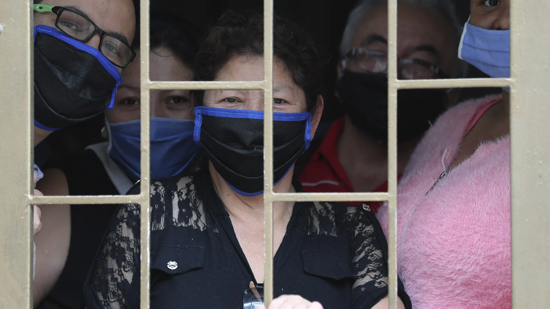 A family peers from their home's window before receiving boxes of free food during a lockdown to prevent the spread of the new coronavirus in Bogota, Colombia, Monday, May 4, 2020. The city government is distributing food to poor people who can't go out to work. (AP Photo/Fernando Vergara)