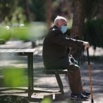 Un anciano con mascarilla descansa en el Parque Calero, en el distrito de Ciudad Lineal