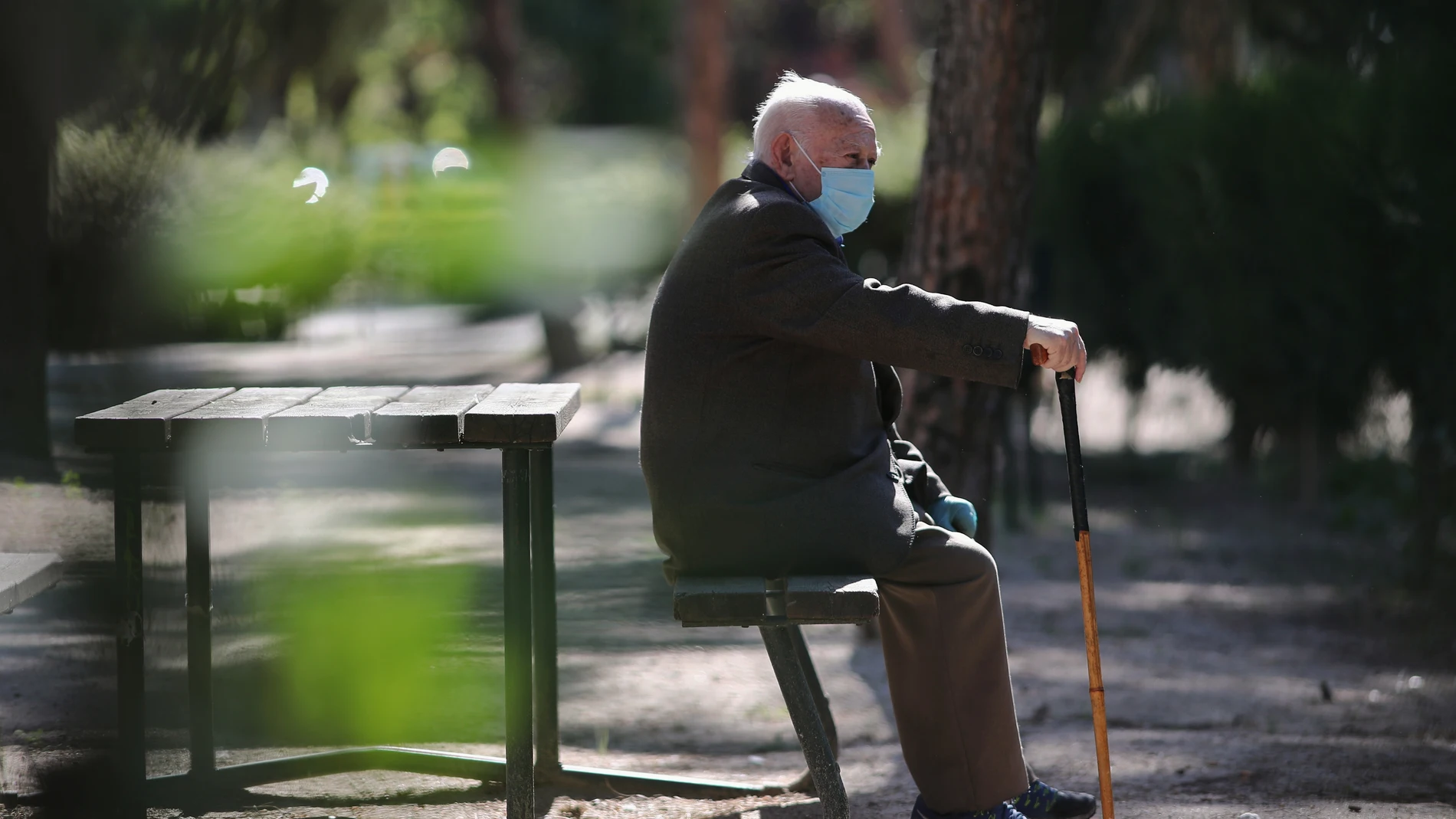 Un anciano con mascarilla descansa en el Parque Calero, en el distrito de Ciudad Lineal
