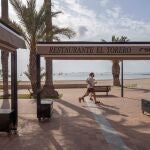 Dos personas pasan junto a la terraza de un restaurante en el paseo de la playa de Barnuevo, San Javier