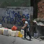 Una mujer con dos garrafas de agua en el barrio de Petare, uno de los más pobres de Caracas