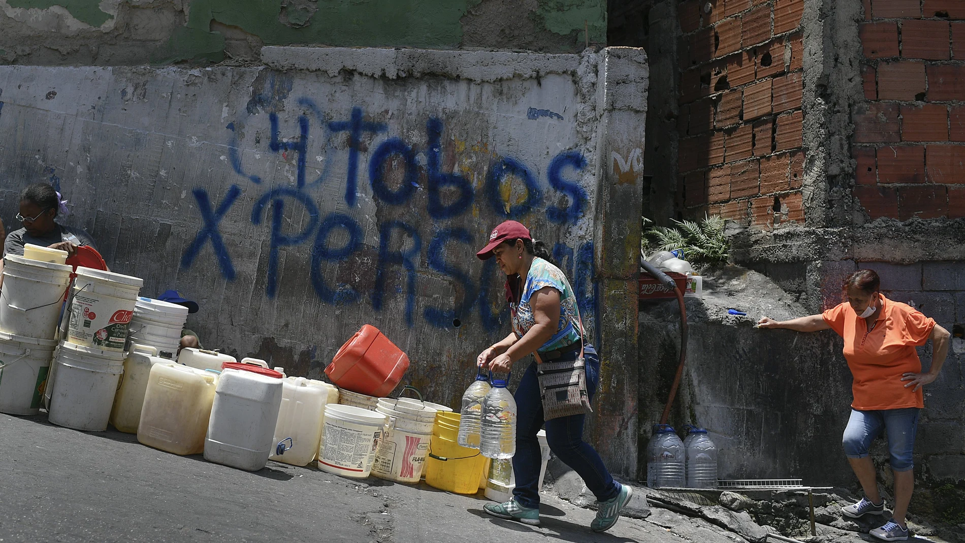 Una mujer con dos garrafas de agua en el barrio de Petare, uno de los más pobres de Caracas