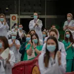 Decenas de miembros del personal sanitario protegidos con mascarilla sostienen carteles durante la concentración de sanitarios en el Día Internacional de la Enfermería