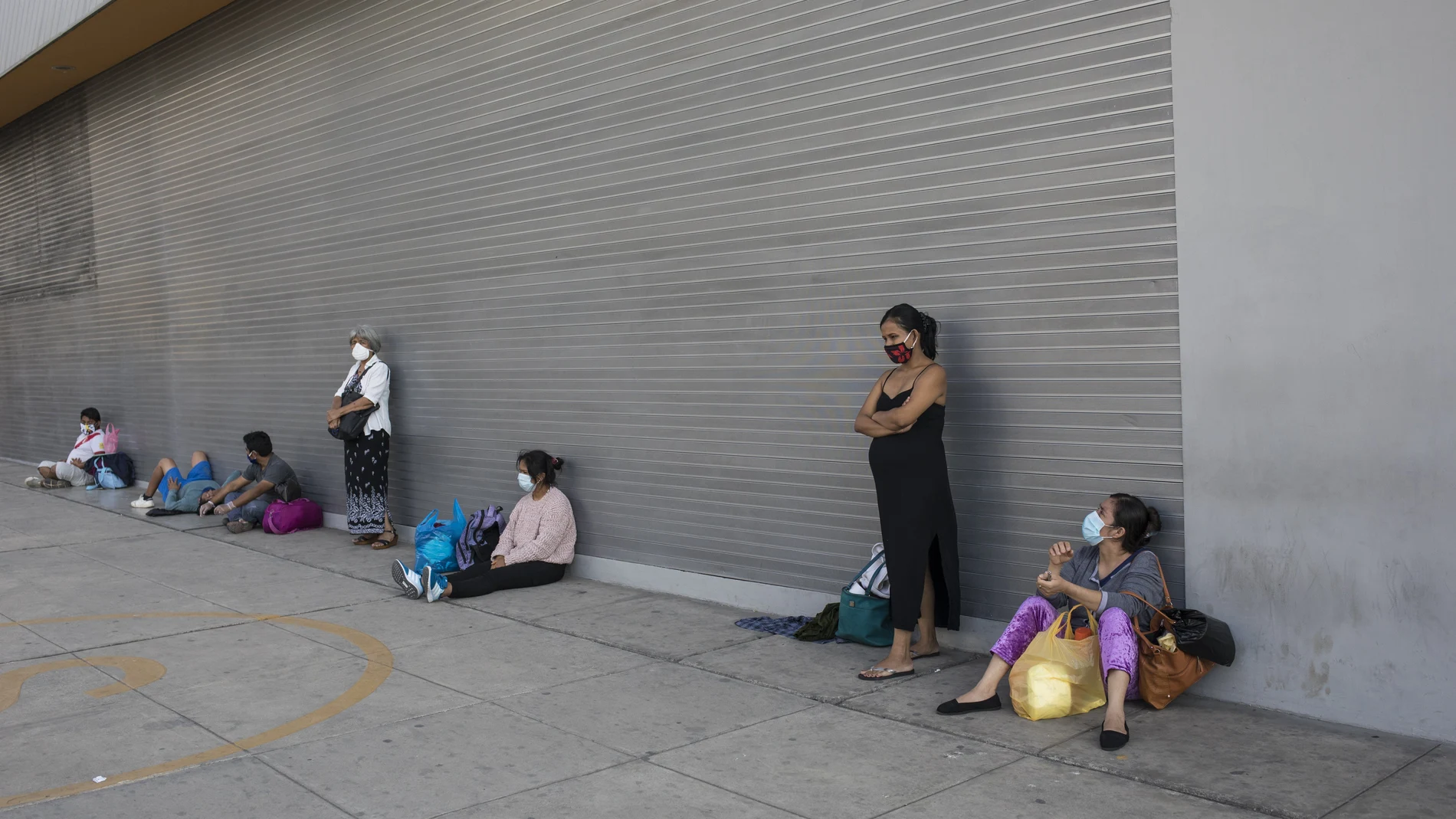 Wearing masks against the spread of the new coronavirus, people wait outside a public hospital, in Lima, Peru, Tuesday, May 12, 2020. The line of those waiting is of both patients and relatives of patients. (AP Photo/Rodrigo Abd)