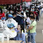 Sanitarios hacen pruebas a ciudadanos chinos en una fábrica de Wuhan