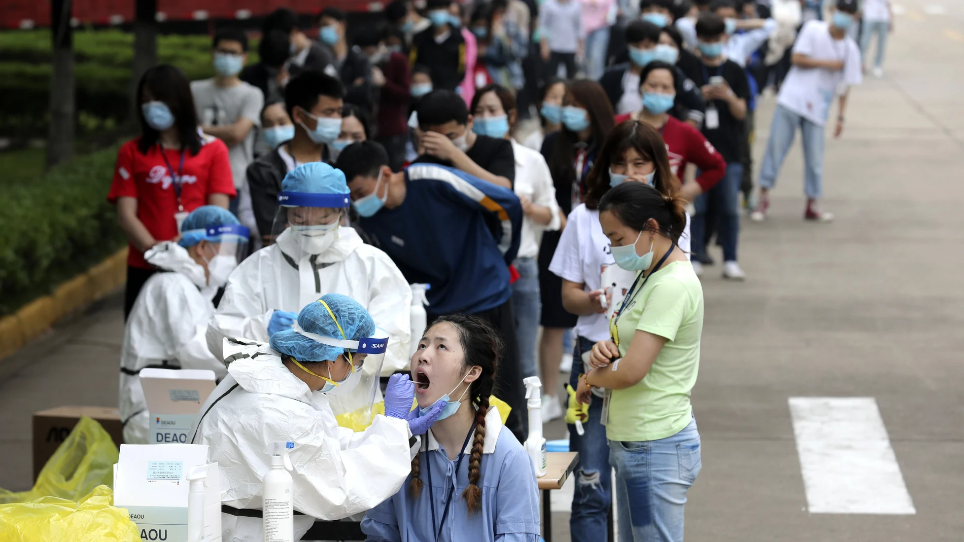 Sanitarios hacen pruebas a ciudadanos chinos en una fábrica de Wuhan