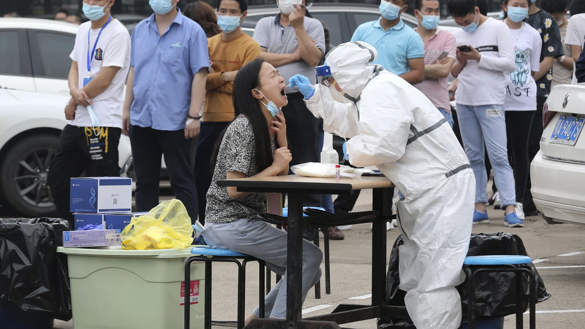 Trabajadores de una fábrica hacen fila en Wuhan para que les hagan un test