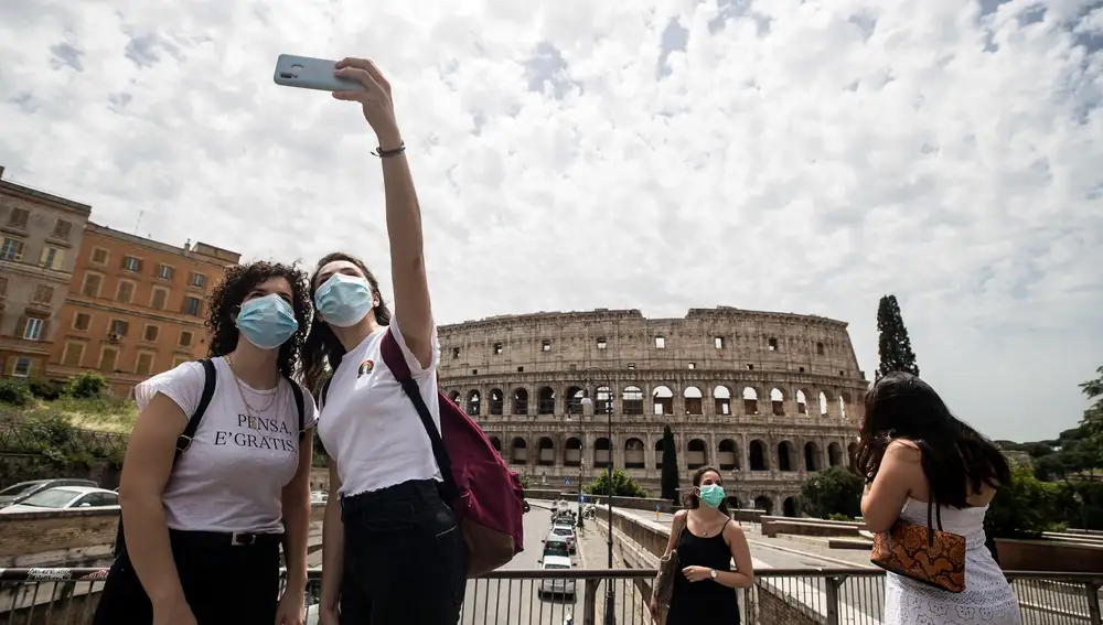 Dos amigas con mascarilla se hacen fotos frente al Coliseo