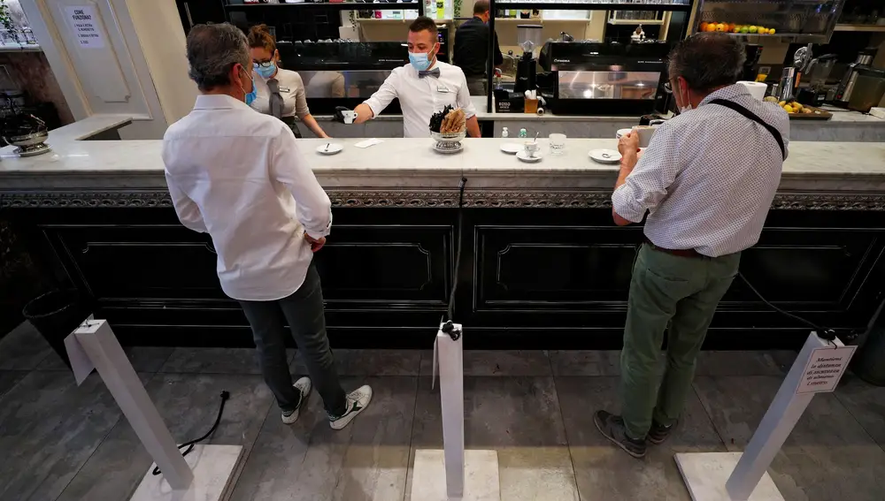 Un camarero con mascarilla y guantes sirve un café en barra en Roma