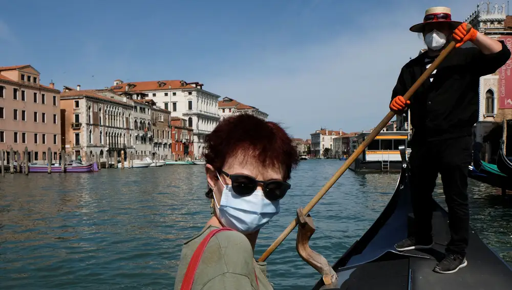 Una mujer con mascarilla se sienta en una góndola del Gran Canal, en Venecia