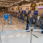Viajeros mantienen la distancia de seguridad antes de facturar su equipaje en el interior del Aeropuerto de Palma