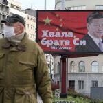 Un hombre camino cerca de un cartel con la foto de Xin Jinping