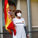 Una mujer protegida con mascarilla sostiene una bandera de España delante de una imagen de Pedro Sánchez durante la manifestación celebrada en la puerta de la sede del PSOE de la calle Ferraz de Madrid, contra la gestión del Gobierno de España contra el coronavirus