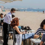 Varias personas disfrutan en la terraza de un bar junto a la playa en Valencia