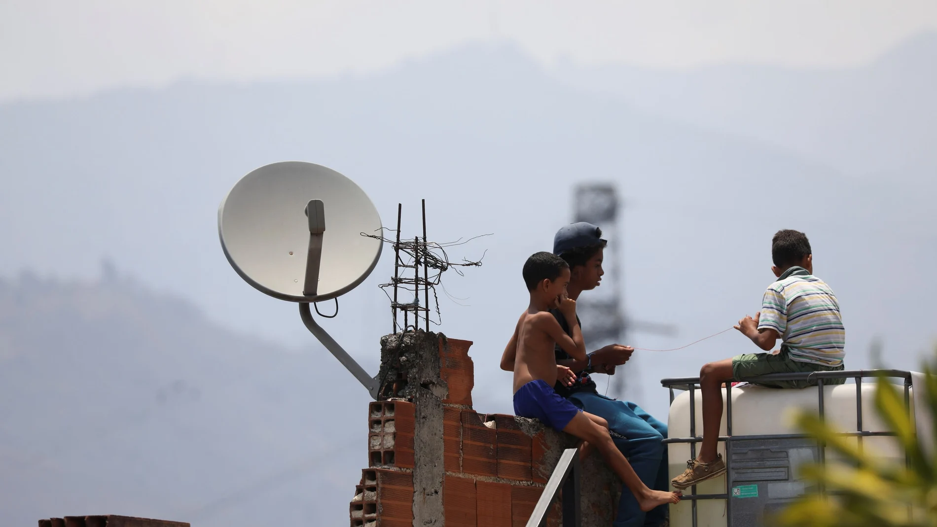 Children play near a satellite tv antenna in the low-income neighbourhood Catia after AT&T Inc said on Tuesday it has closed its DirecTV Latin America operations in Venezuela, in Caracas