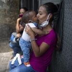 Una madre besa a su bebé, ambos con mascarillas, en una calle de Caracas, Venezuela
