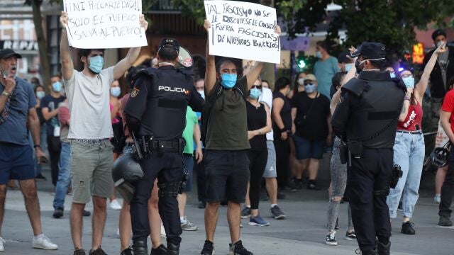 Jóvenes antifascistas muestran sus pancartas frente a la manifestación que vecinos del madrileño barrio de Carabanchel protagonizan hoy jueves junto a la Avenida de Oporto para protestar contra la gestión del Gobierno