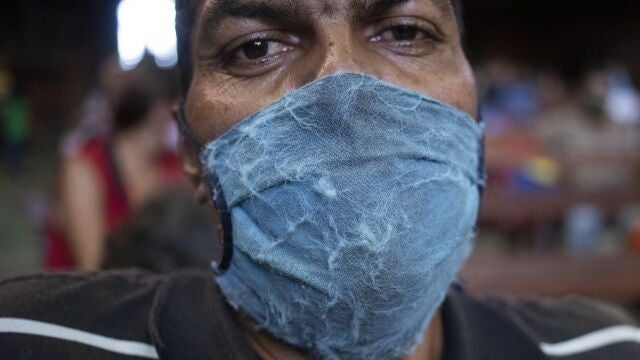 Una hombre se cubre el rostro de manera precaria mientras espera ayuda humanitaria en la iglesia del barrio de El Cementerio de Caracas.