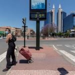 Una mujer pasa junto a un termómetro urbano que marca 39º, en Murcia