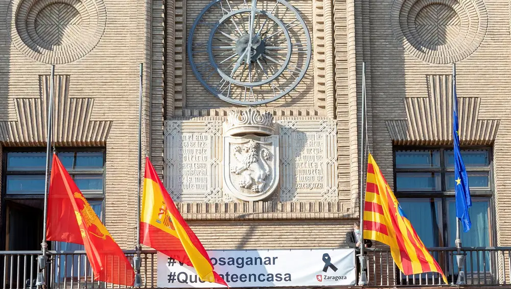 Un funcionario del Ayuntamiento de Zaragoza coloca las banderas a media asta