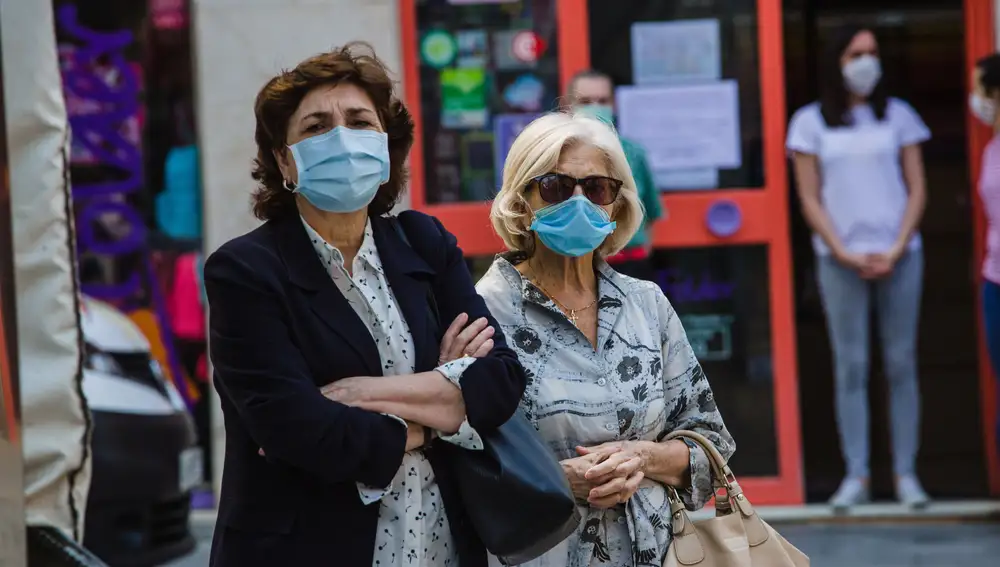 Dos mujeres guardan un minuto de silencio por las víctimas de la Covid-19 junto a la sede de la subdelegación del Gobierno en Soria