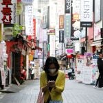 Una mujer camina mientras mira su móvil en el distrito comercial de Seúl