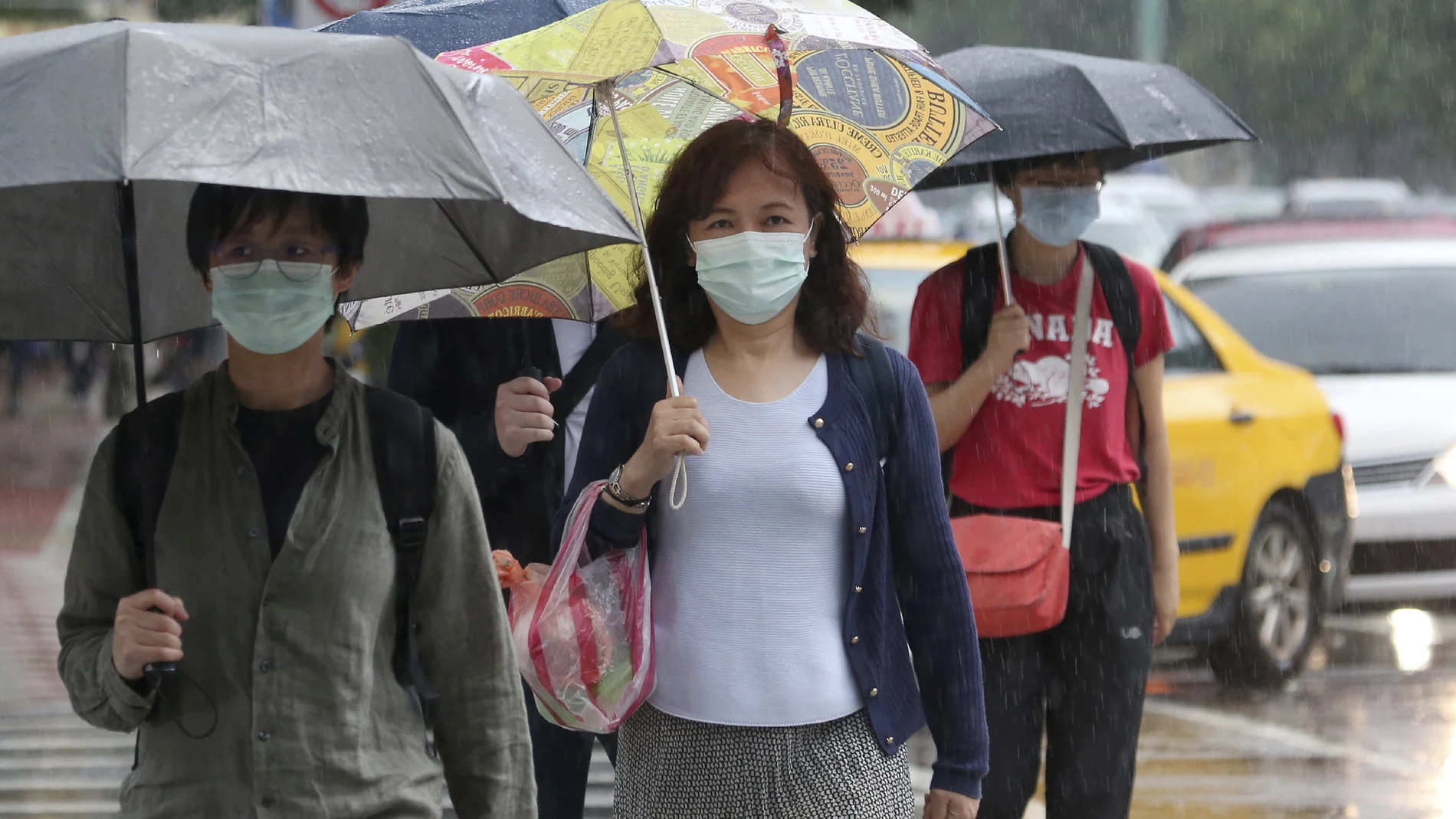 Taiwaneses caminan con mascarilla y paraguas por el centro de Taipéi