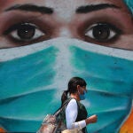 Una mujer pasea ante un mural sobre el coronavirus en Ciudad de México