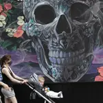 Unos padres con mascarillas pasean por Nueva York frente a un mural