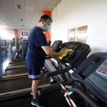 Un trabajador desinfecta una máquina de un gimnasio