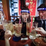 Un grupo de amigos con protectores de plástico brindan en un pub de Osaka (Japón)