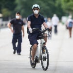 Un hombre protegido con mascarilla y guantes monta en una bicicleta BiciMAD