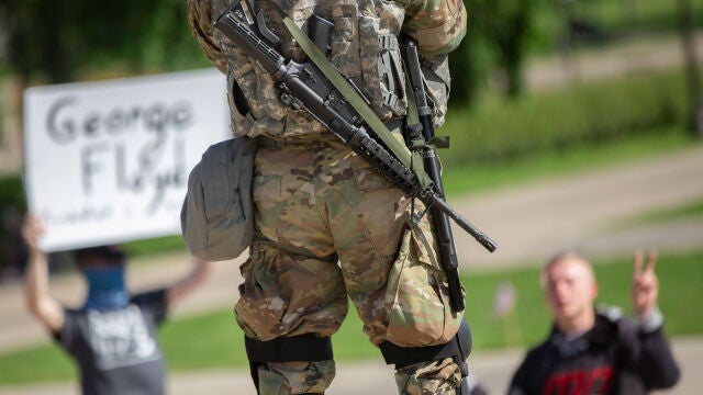 Dos hombres protestan delante de un miembro de la Guardia Nacional en Minneapolis