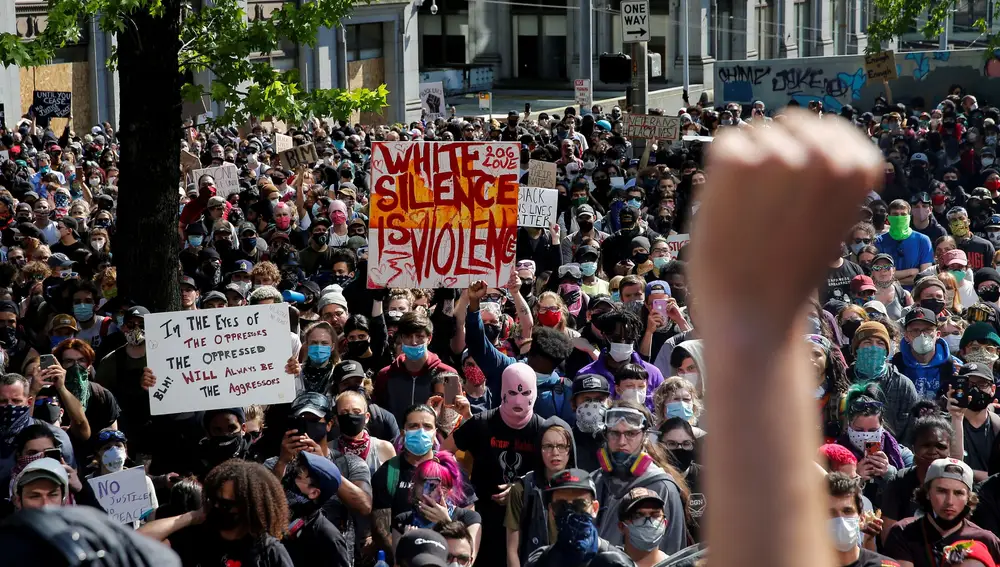 Un grupo de manifestantes alzan sus puños durante una protesta frente al Ayuntamiento de Seattle.